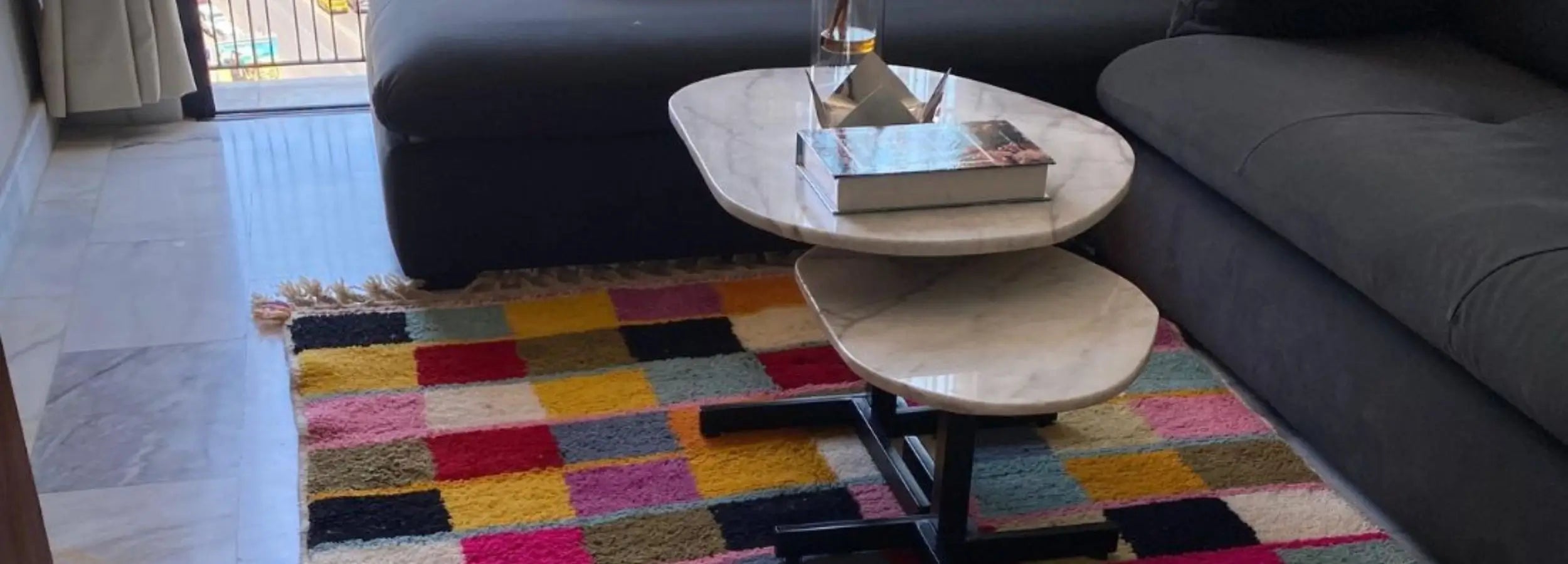 Tapis berbère coloré fait main en laine, dans un salon moderne avec canapé gris.