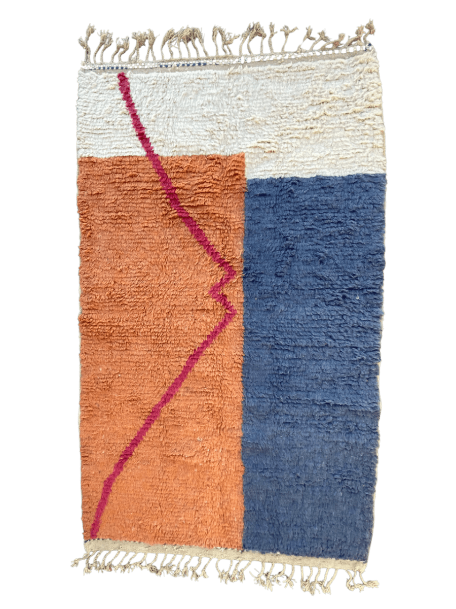 Tapis Beni Ouarain Anzar 258×154 cm, design moderne bleu et terracotta, motif rose géométrique et franges écrues.