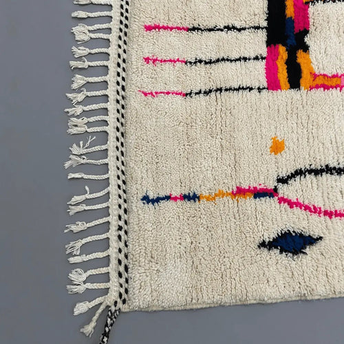 Détail du tissage en laine naturelle du tapis Azilal – couleurs vives rose, orange et bleu sur fond crème