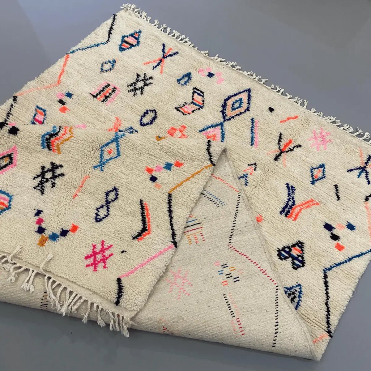 Tapis berbère fait main en laine naturelle – recto verso visible avec tissage traditionnel marocain