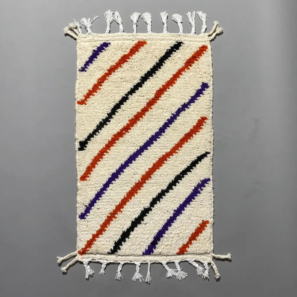 Motifs géométriques multicolores d’un petit tapis artisanal Azilal en laine naturelle, fait main au Maroc.