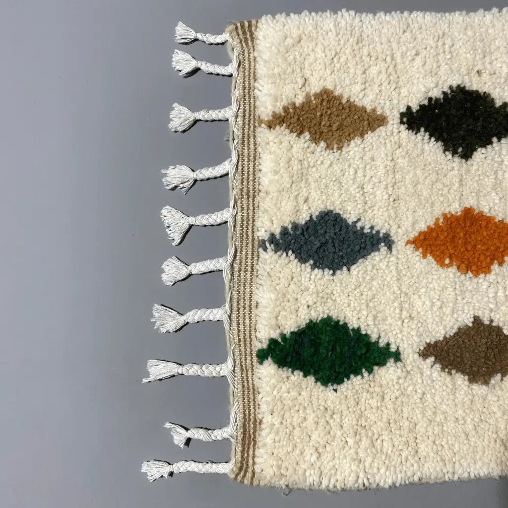 Modèle unique Azilal 104×62 cm, tissé main, motifs traditionnels et couleurs éclatantes."